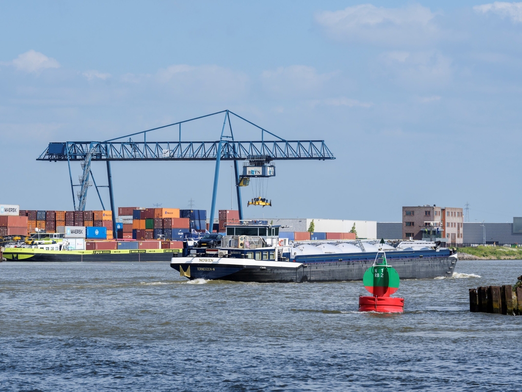 Foto eines Containerterminals in einem Hafen, im Vordergrund ein Schiff